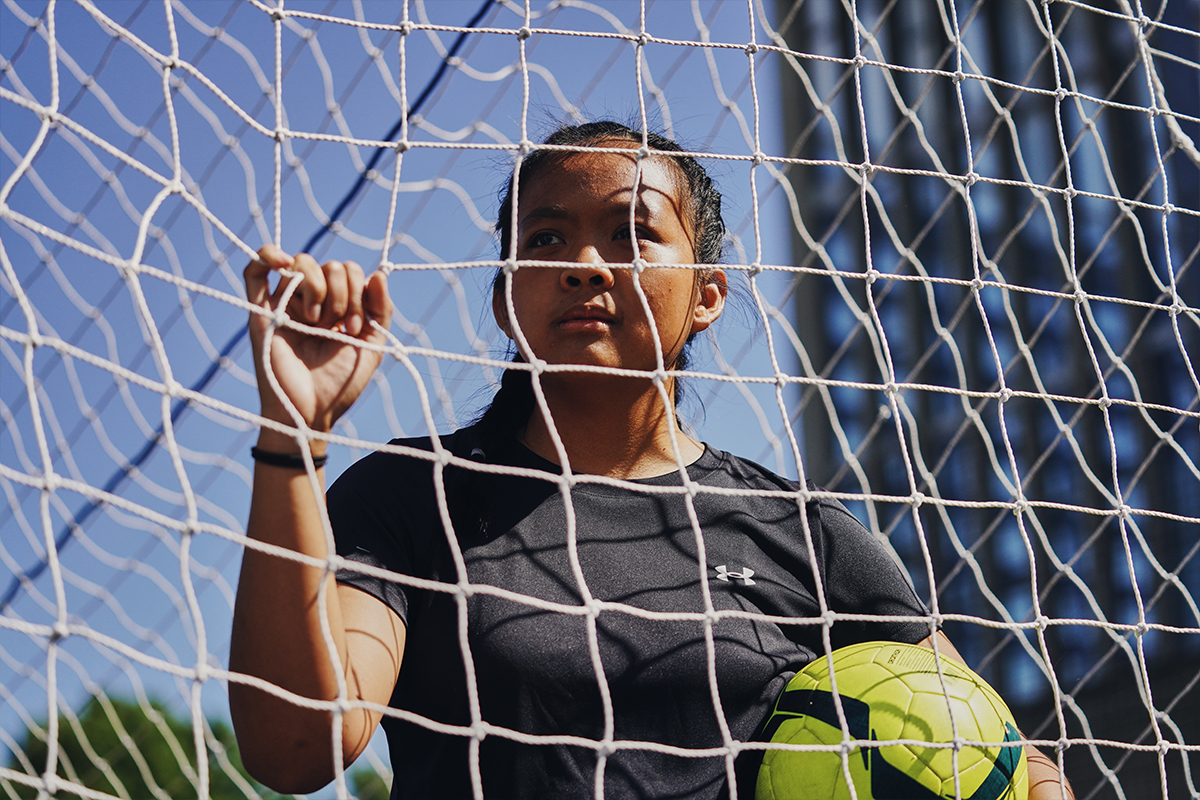 Girl standing in the net holding a football